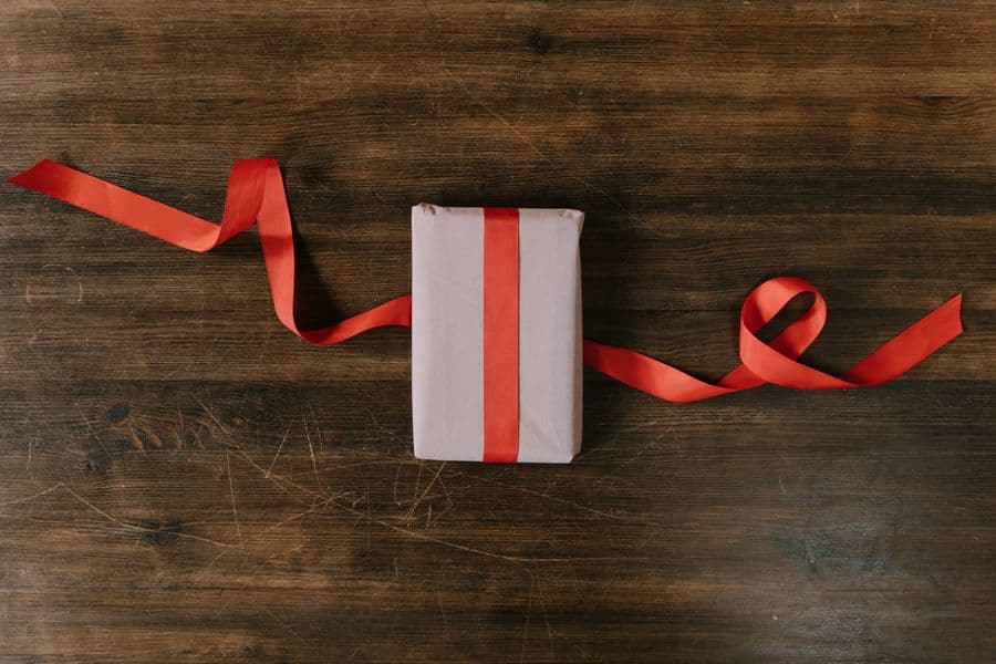 A wrapped gift with a red ribbon on a wooden workbench